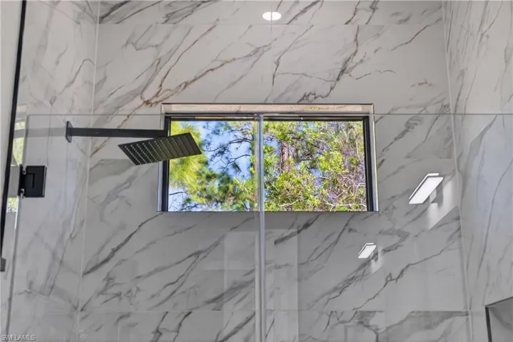 Bathroom featuring vanity, a marble finish shower, marble finish floors, and recessed lighting