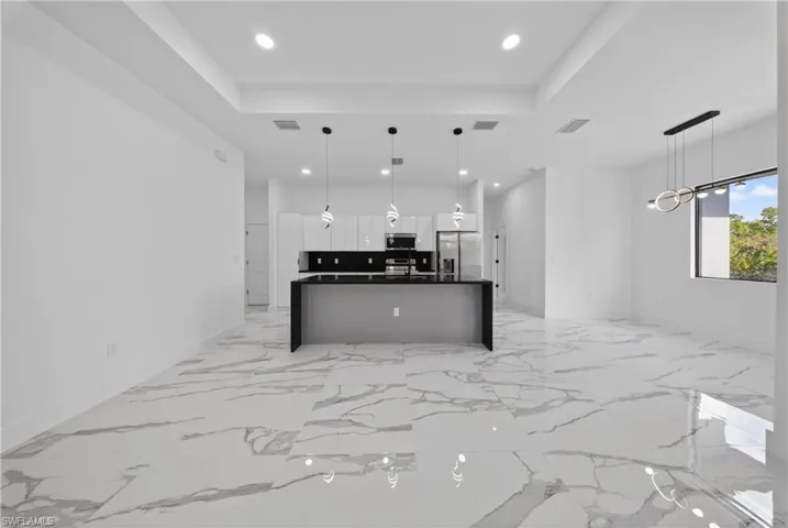 Unfurnished living room featuring ceiling fan, recessed lighting, and a tray ceiling