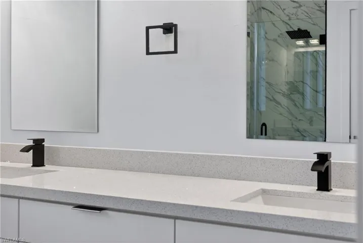 Full bathroom with double vanity, a marble finish shower, and light marble finish flooring