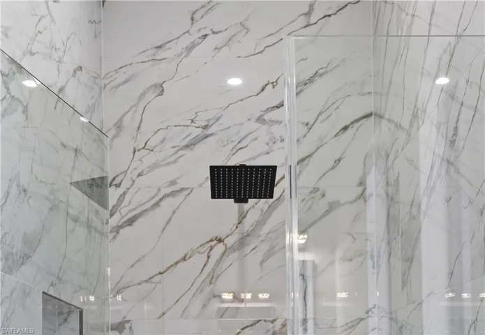 Full bath with a marble finish shower