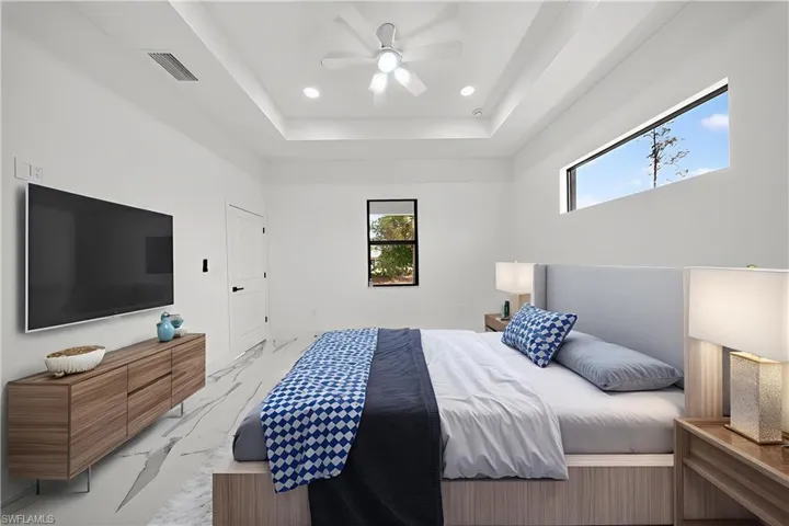 Unfurnished bedroom with recessed lighting, ceiling fan, and a tray ceiling