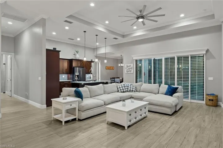 Living room featuring ceiling fan, light wood-type flooring, and ornamental molding
