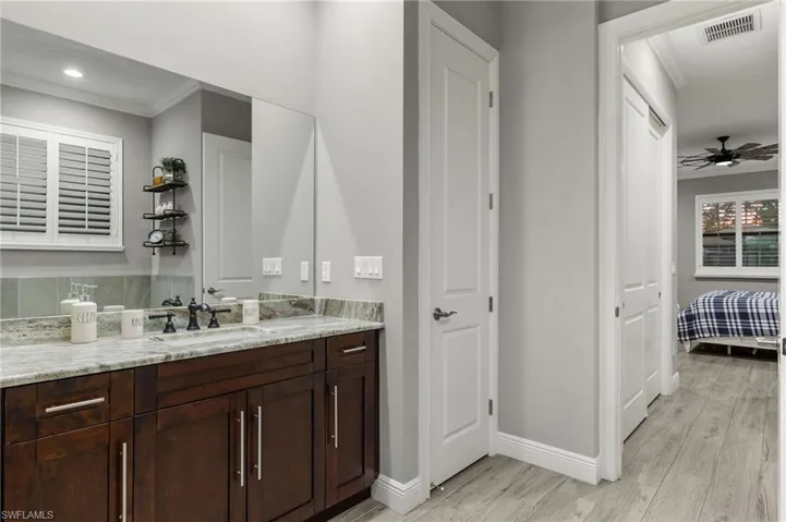 Bathroom with wood-type flooring, backsplash, ornamental molding, ceiling fan, and vanity