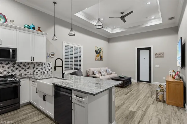 Kitchen with stainless steel appliances, a raised ceiling, sink, and white cabinetry