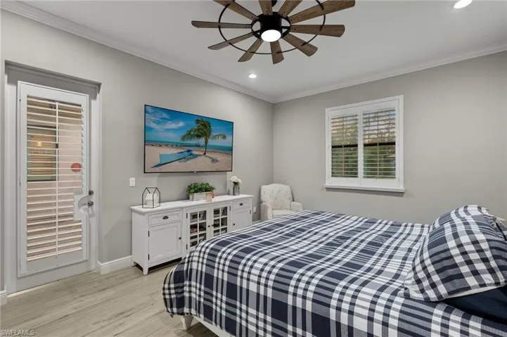 Bedroom featuring ceiling fan, light hardwood / wood-style flooring, and crown molding