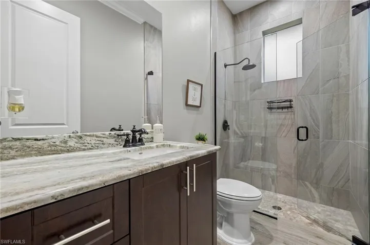Bathroom with vanity, a shower with shower door, and toilet