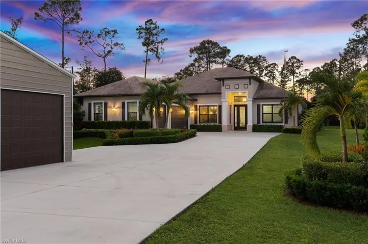View of front facade featuring a garage and a lawn