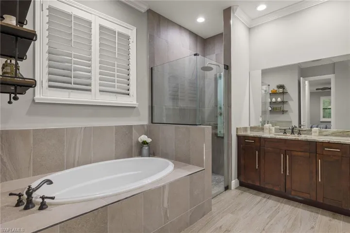 Bathroom featuring independent shower and bath, vanity, hardwood / wood-style floors, and ornamental molding