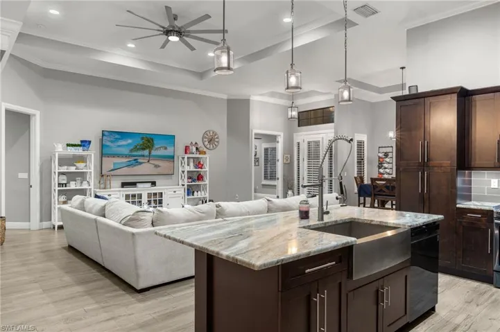 Kitchen featuring black dishwasher, a kitchen island with sink, sink, light hardwood / wood-style flooring, and ceiling fan