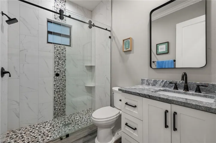 Bathroom featuring walk in shower, vanity, toilet, and hardwood / wood-style flooring