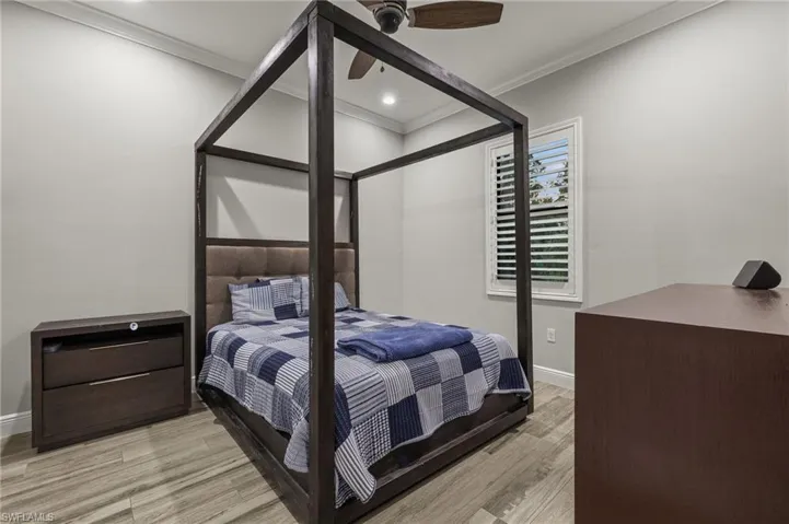 Bedroom featuring ceiling fan, crown molding, and light hardwood / wood-style floors