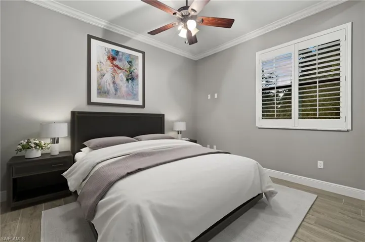 Bedroom with ceiling fan, light wood-type flooring, and ornamental molding