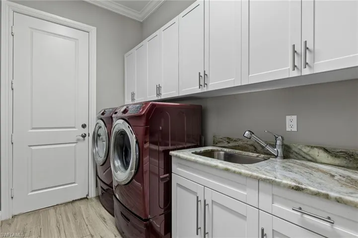 Washroom featuring light hardwood / wood-style floors, separate washer and dryer, cabinets, ornamental molding, and sink