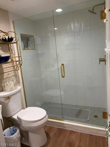 Glass-enclosed shower with gold-finish hardware, white subway tile surround, and mosaic tile flooring