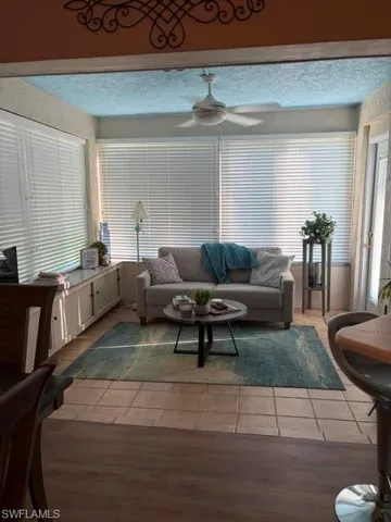 Sunroom featuring extensive window coverage, a ceiling fan, tiled flooring, and built-in white cabinetry