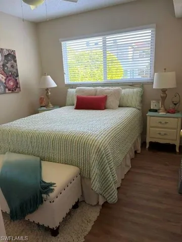 Room featuring a large window with horizontal blinds, wood-finish flooring, and a ceiling fan