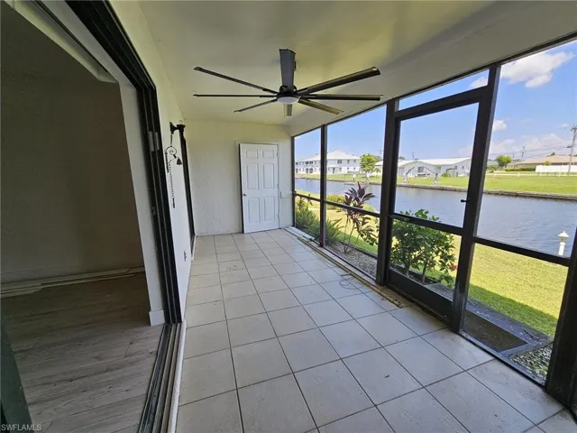 Unfurnished sunroom featuring ceiling fan and a water view