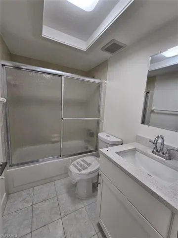 Guest Full bathroom featuring tile patterned flooring, toilet, bath / shower combo with glass door, and vanity