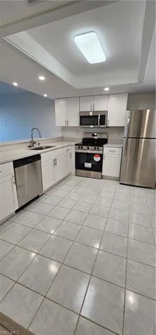 Kitchen with stainless steel appliances, white cabinetry, light tile patterned flooring, light countertops, and recessed lighting