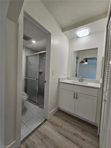 Bathroom with an enclosed shower, toilet, vanity, and hardwood / wood-style flooring