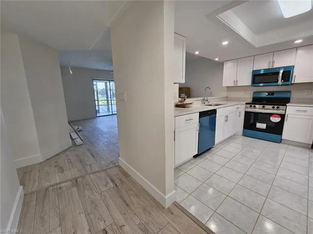 Kitchen with dishwasher, sink, electric range, light wood-type flooring, and white cabinets