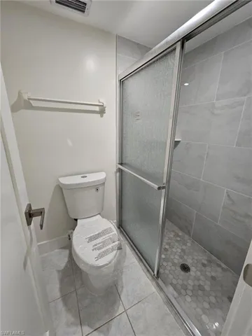 Bathroom with tile patterned flooring, an enclosed shower, and toilet