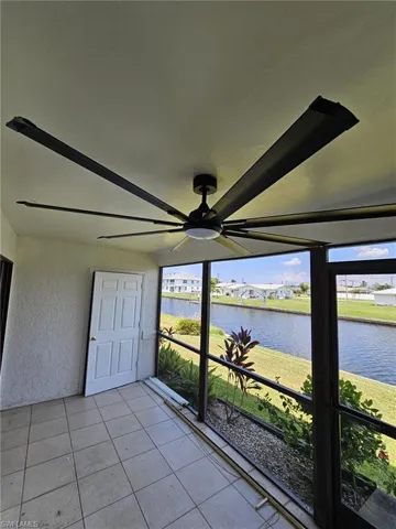 Unfurnished sunroom featuring ceiling fan, a water view, and a healthy amount of sunlight