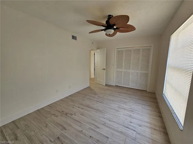 Guest  bedroom featuring ceiling fan, light wood-type flooring, a closet, and multiple windows