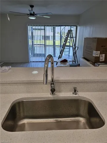 Interior details with ceiling fan, sink, and light stone countertops