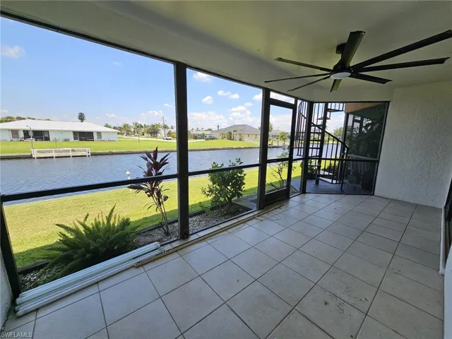 Unfurnished sunroom featuring ceiling fan and a water view