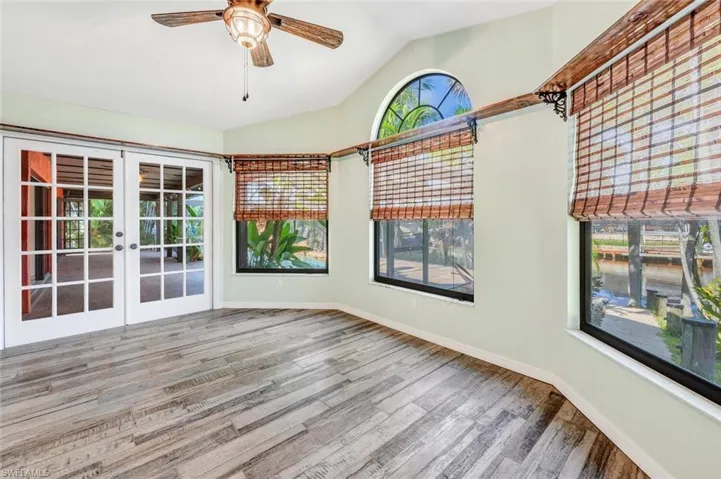 Unfurnished sunroom with ceiling fan, french doors, and lofted ceiling