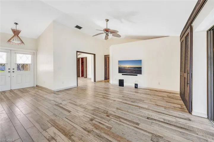 Unfurnished living room featuring light wood-type flooring, ceiling fan, french doors, and lofted ceiling