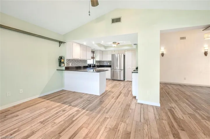 Kitchen with stainless steel refrigerator, white cabinetry, ceiling fan, and kitchen peninsula