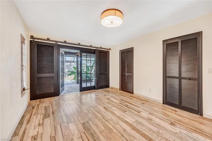 Unfurnished bedroom with french doors, a barn door, light hardwood / wood-style floors, and access to exterior