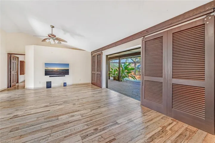 Unfurnished living room with ceiling fan, light hardwood / wood-style floors, and lofted ceiling