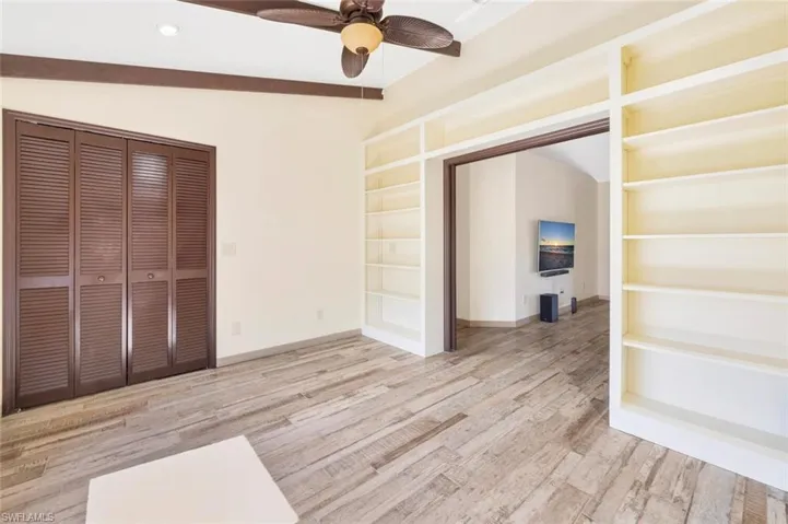 Unfurnished bedroom with lofted ceiling with beams, ceiling fan, and light wood-type flooring