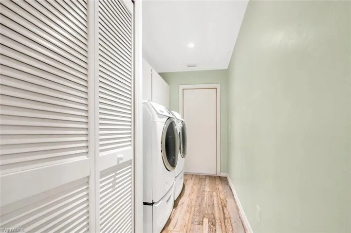 Laundry area with washing machine and dryer and light hardwood / wood-style flooring
