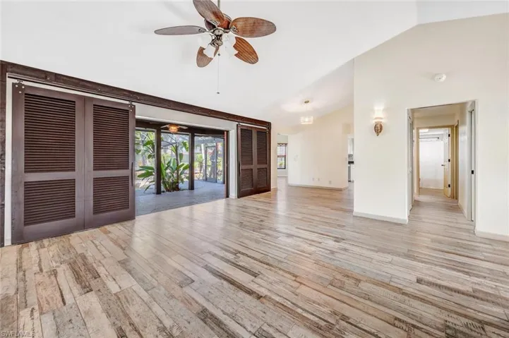 Unfurnished room with ceiling fan, light wood-type flooring, and lofted ceiling