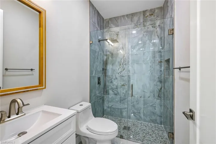 Bathroom featuring a shower with shower door, vanity, and toilet