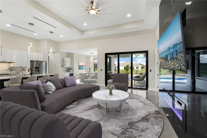 Living room featuring tile floors, ceiling fan, a towering ceiling, and a raised ceiling