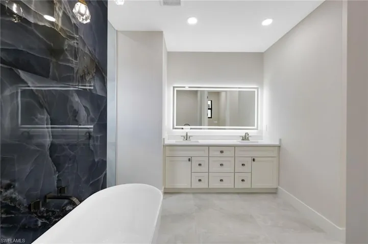 Bathroom featuring tile flooring, double sink, shower with separate bathtub, and vanity with extensive cabinet space