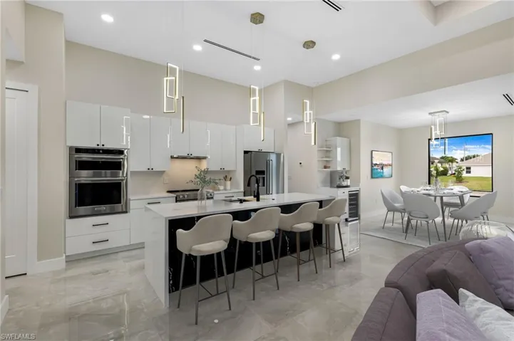 Kitchen with white cabinets, hanging light fixtures, a kitchen island with sink, and appliances with stainless steel finishes