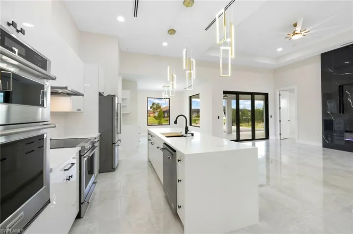 Kitchen featuring ceiling fan, stainless steel appliances, decorative light fixtures, light tile floors, and sink