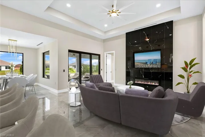 Tiled living room featuring a large fireplace, plenty of natural light, and a raised ceiling