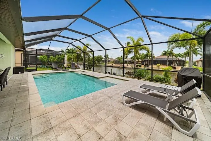 View of swimming pool featuring a water view, area for grilling, a patio, and glass enclosure