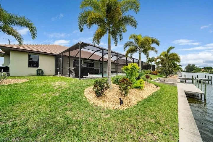 View of yard featuring a water view, a boat dock, and glass enclosure