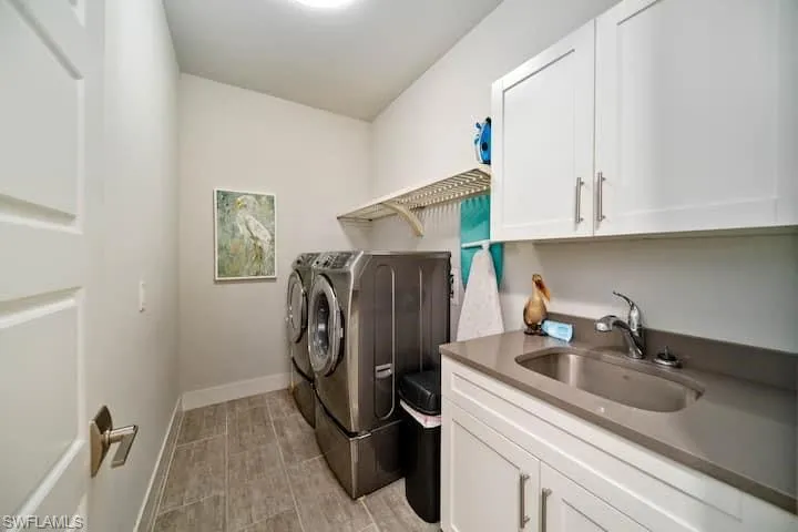Washroom with sink, cabinets, and independent washer and dryer