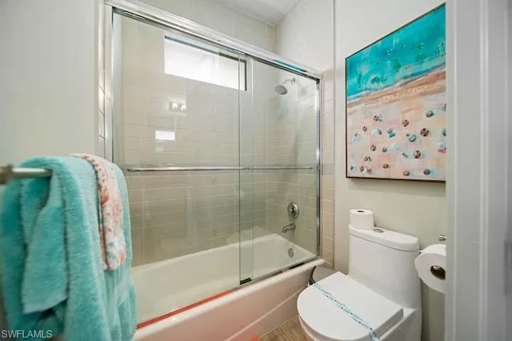 Bathroom with enclosed tub / shower combo and toilet