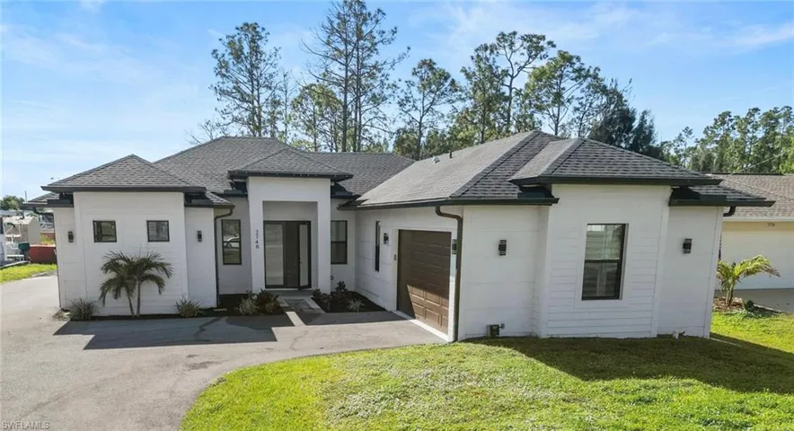 View of front of property featuring a shingled roof, a front yard, asphalt driveway, and an attached garage