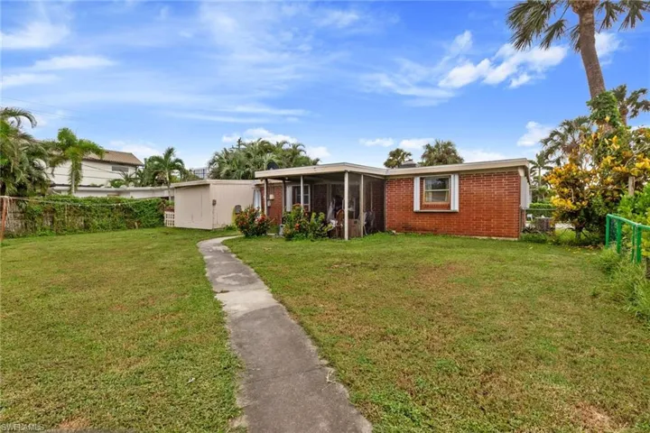 View of front of home with a shed and a front lawn